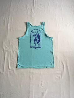 "vintage 1990s tank top shirt Hanes Beefy T 100% cotton, made in USA single stitch sea foam green w/image on back- front of shirt is blank back- print of 2 men playing volleyball (1 on each side of net w/ball in air) writing- Beva Summer Doubles 1991 good vintage condition, light wear-light stain- see photos label size L, see below measures, lying flat, shoulder-12\" chest-20\" length-28\"" Green Graphic Print Sleeveless Tank Top, Summer Muscle Tee For Gym, Summer Gym Cotton Top, Summer Cotton Gym Top, Cotton Gym Top For Summer, Cotton Top For Gym In Summer, Vintage Tank T-shirt For Summer, Green Graphic Print Cotton Tank Top, Pre-shrunk Cotton Sleeveless T-shirt