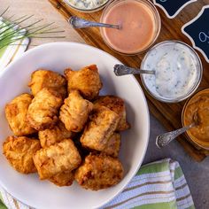 a plate full of tater tots next to dips and sauces on a table