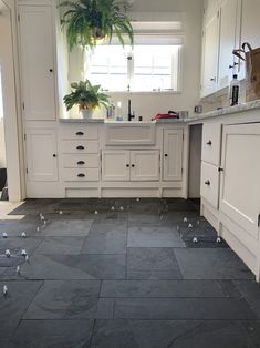 a kitchen with black slate flooring and white cabinetry is shown in this image