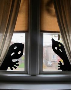 the window is open and there are two black cats looking out at the street outside