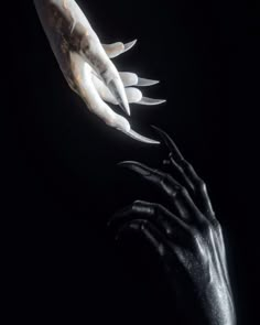 two hands reaching out towards each other in the dark, with their claws extended up