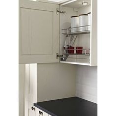 an open cabinet with pots and pans on the bottom shelf in a white kitchen