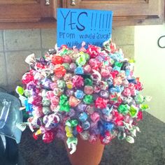 a potted plant that has been made out of small candy wrappers and is sitting on the kitchen counter