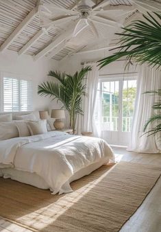 a large bed sitting under a window next to a potted plant in a bedroom