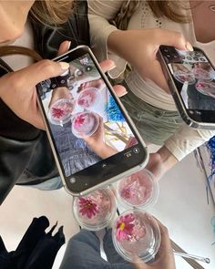 two women holding up their cell phones with pictures on them and flowers in the screen