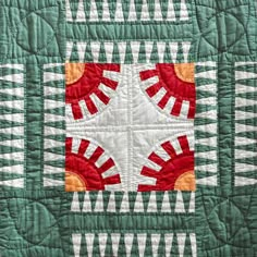 a green and white quilt with an orange center