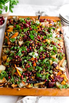 a wooden cutting board topped with lots of veggies and grains on top of it