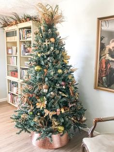 a decorated christmas tree in a living room next to a chair and bookshelf