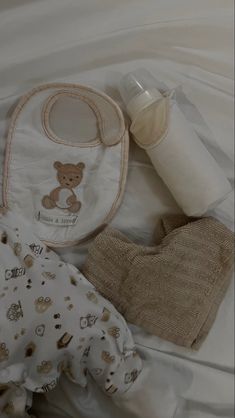 a baby's diaper, bottle and bib laying on a white sheet