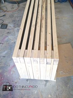 a wooden bench sitting on top of a floor next to a pile of plywood