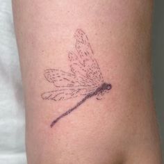 a small dragonfly tattoo on the arm