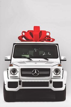 a white mercedes g - class with a red bow on top