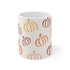 a white mug with orange and yellow pumpkins on it