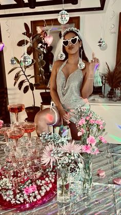 a woman sitting at a table with wine glasses and flowers in vases on it