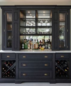 a black cabinet with wine glasses and bottles on the top is in front of a window