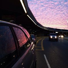 two cars driving down the road under a purple sky