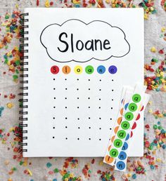 a notebook with the word sloane written on it next to some colorful sprinkles