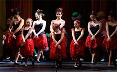 a group of women in red dresses on stage