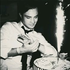 a man sitting at a table in front of a cake with sparklers on it