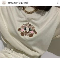 a woman wearing a white shirt with a monkey embroidered on it