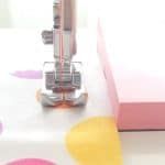 the sewing machine is on top of the pink and white tablecloths with circles around it