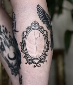 a woman's legs with tattoos on them and an oval frame in the middle