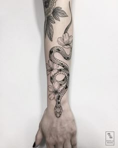 a woman's arm with a snake and flowers tattoo on it