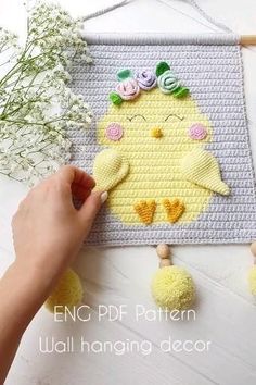 a person is making a crocheted chicken wall hanging decoration with flowers on it