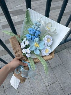 a person holding a bouquet of flowers on top of a wooden chair next to a brick walkway