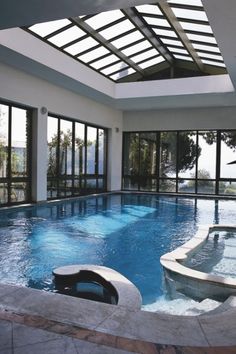 an indoor swimming pool with glass doors leading to the patio and hot tub in the center