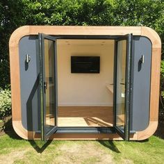 a small wooden structure with glass doors in the grass