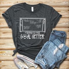 a t - shirt that says raising a real goal getter on it next to ripped jeans