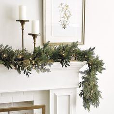 a mantel decorated with greenery and candles