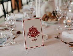 the table is set with wine glasses and place cards