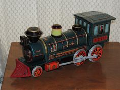 a toy train sitting on top of a wooden table next to a white and gray wall