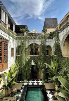 an indoor pool surrounded by greenery and potted plants in the middle of a courtyard