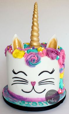 a white cake with a unicorn face and gold horn