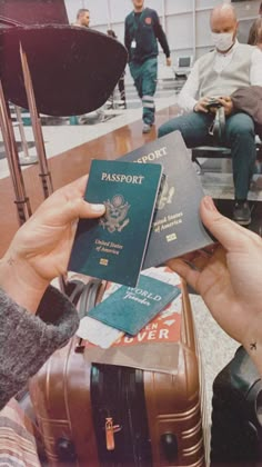 two people are holding their passport and sitting at a table with other people in the background