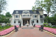 a large white house surrounded by flowers and trees