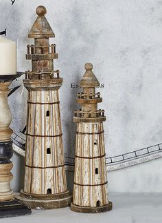 three wooden lighthouses sitting on top of a table next to a white candle holder