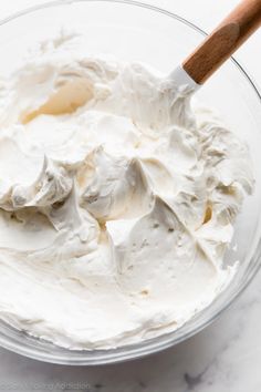 whipped cream in a glass bowl with a wooden spoon