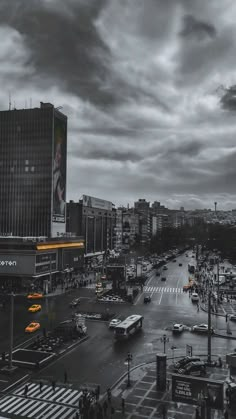 a city street filled with lots of traffic and tall buildings under a cloudy gray sky