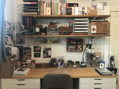 a desk with many books and other items on it, along with a chair in front of the desk