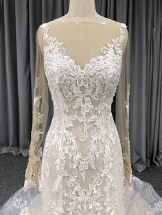 a white wedding dress on display in front of curtains