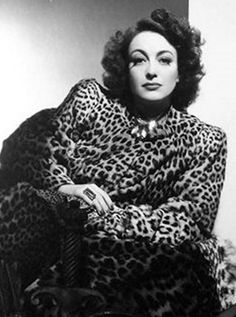 a black and white photo of a woman in a leopard print coat sitting on a chair