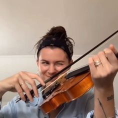 a woman holding a violin in her right hand and wearing a bandana on her head