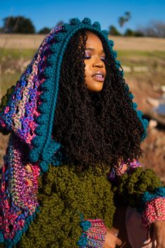 a woman with long curly hair wearing a crocheted shawl