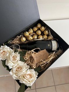 a bottle of wine and some flowers in a box with chocolates on the table