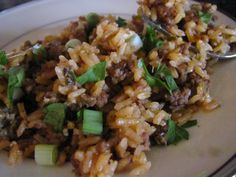 a white plate topped with rice covered in meat and veggies next to a fork