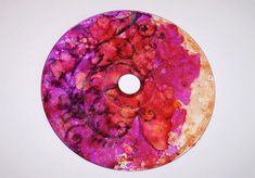 a purple and red disc on a white surface with some paint splatters all over it